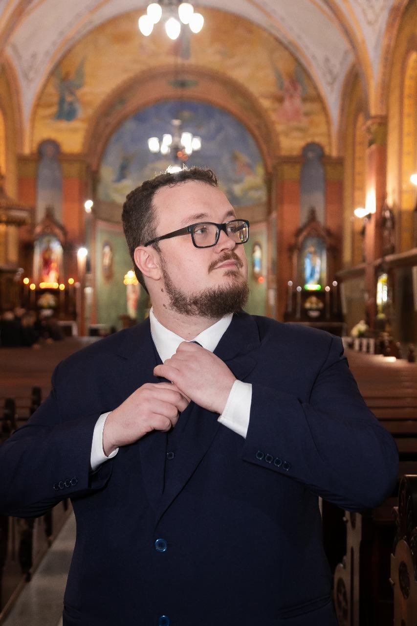 Andrey Beckert Mudri, de terno escuro e óculos, olhando para o alto